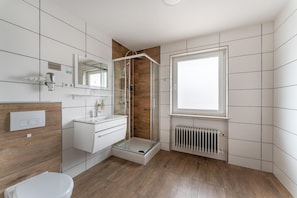 A modern bathroom with a shower, a toilet, and a sink. - Hotel Glas Schwarzwald (Fluorn)