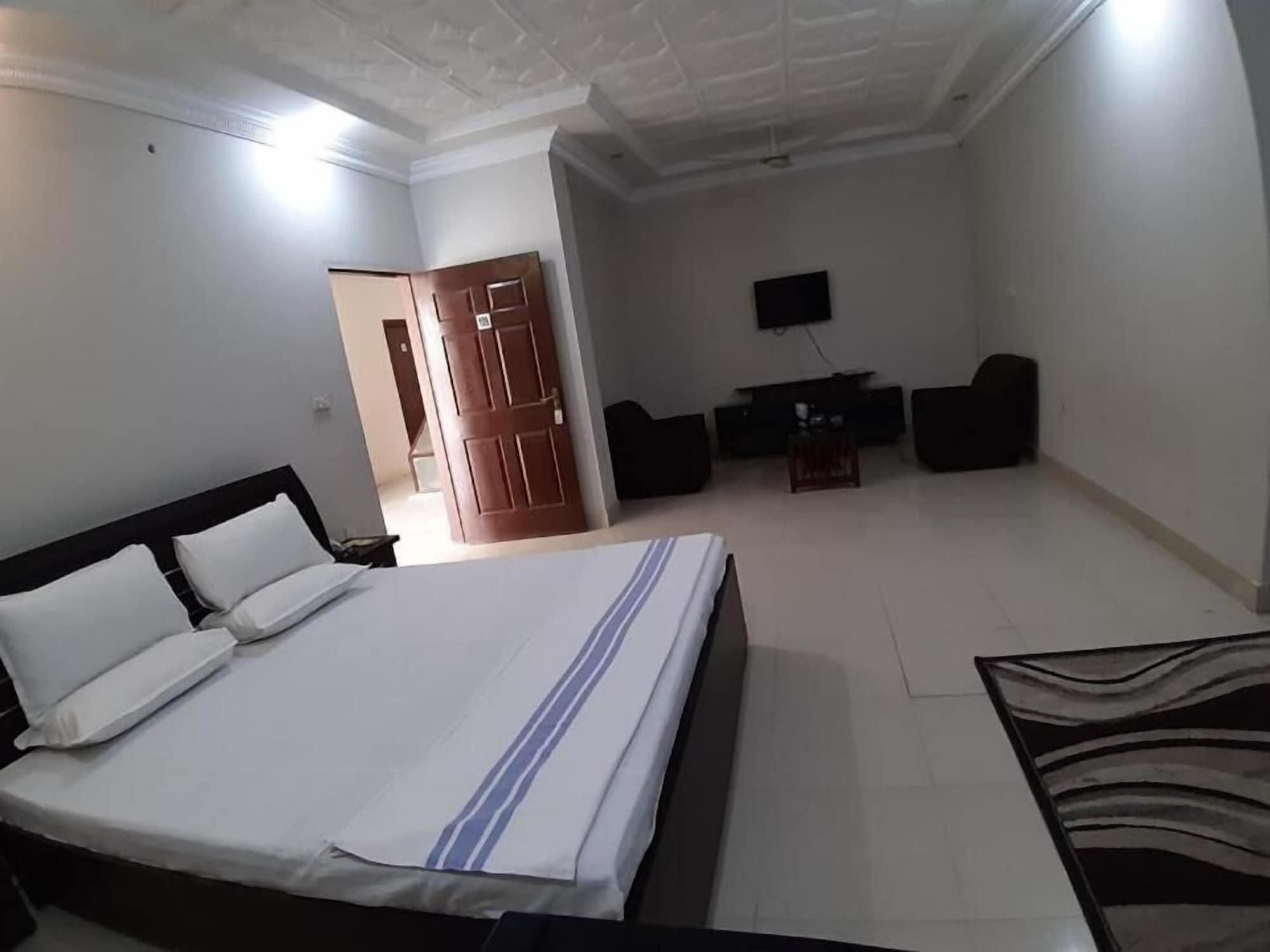 A hotel room with a bed, a TV, a desk, and a chair.