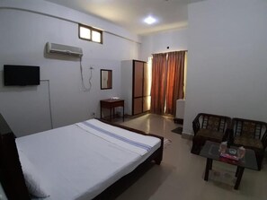 Une chambre d’hôtel équipée d’un lit, d’une télévision, d’un climatiseur, d’un bureau, d’une chaise et d’une table.