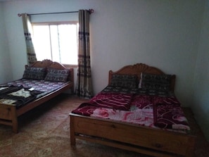 A room with two wooden beds, each with patterned bedding. - Green City Hotel And Restaurant (Balakot)