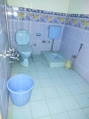 A small bathroom with a toilet, a bidet, a blue bucket, and a yellow container. - Green City Hotel And Restaurant (Balakot)
