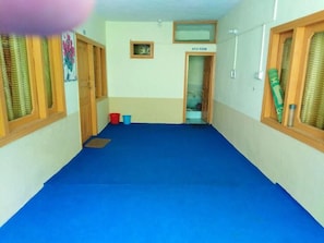 A hallway with a blue carpet, wooden doors, and a sign indicating a washroom. - Green City Hotel And Restaurant (Balakot)