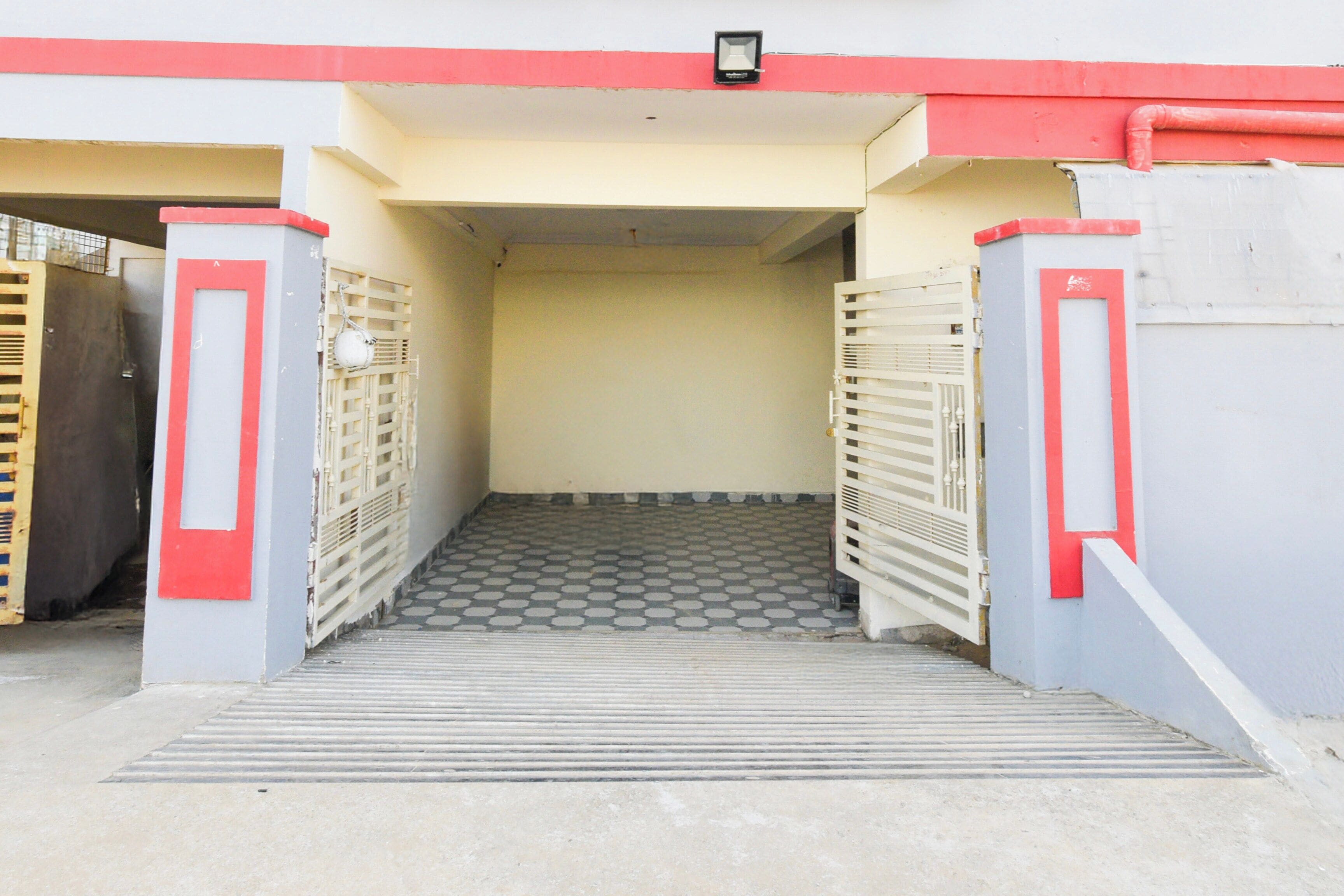 Una entrada con reja y una escalera metálica que conduce a un espacio cubierto.
