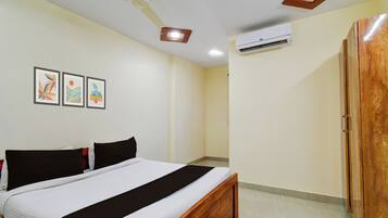 Un dormitorio con una cama, ventilador de techo, unidad de aire acondicionado y cuadros en la pared.