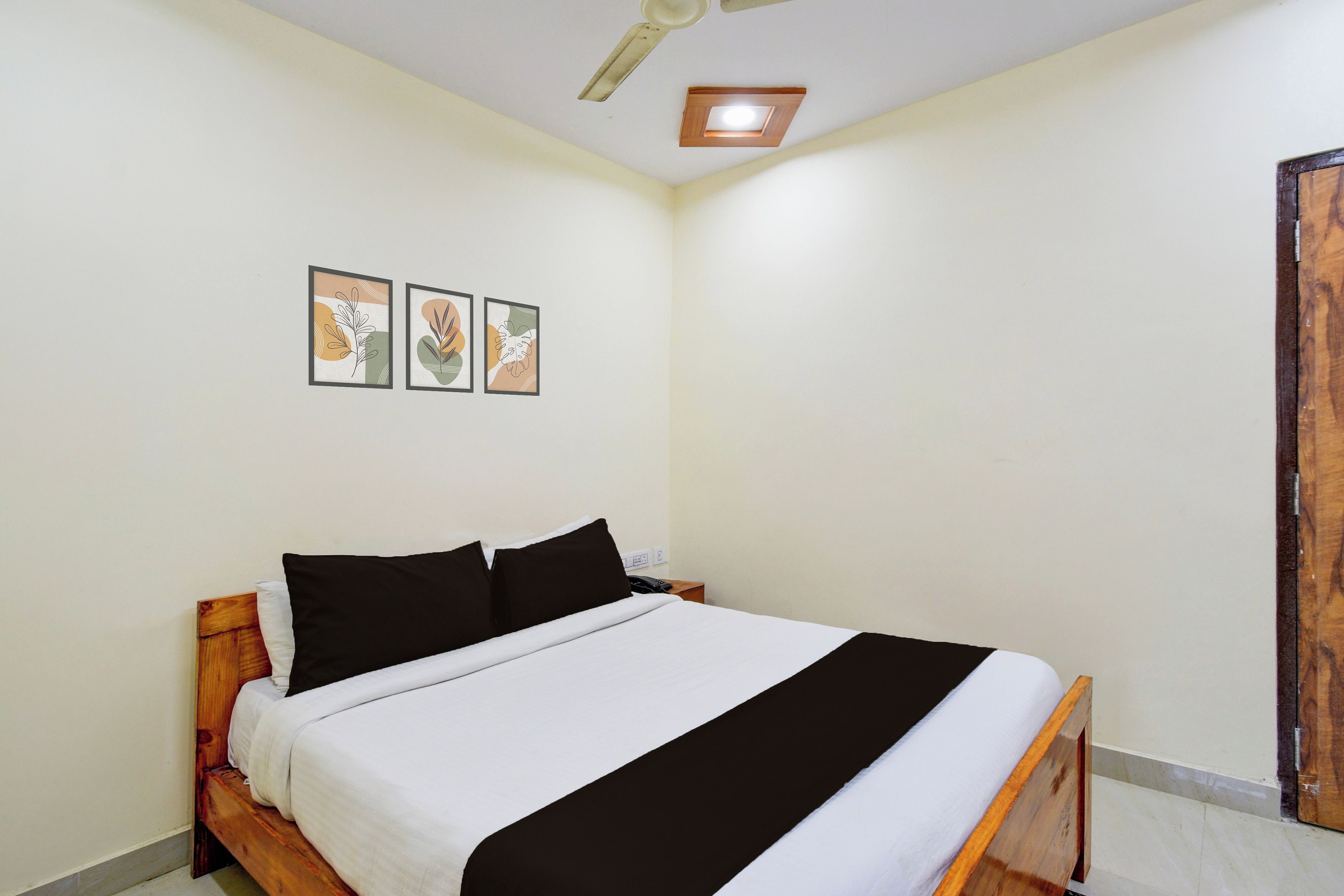 Un dormitorio con una cama, un ventilador de techo y tres cuadros en la pared.