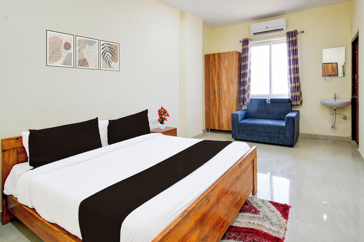 Une chambre à coucher comprenant un lit, une armoire, un canapé, une fenêtre avec des rideaux et une salle de bain avec un lavabo.