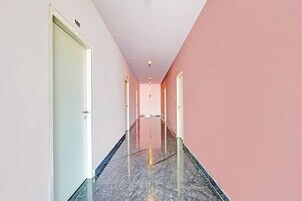 Ein Korridor mit Türen an beiden Seiten, einem Fliesenboden und einer Decke mit eingelassenen Leuchten.