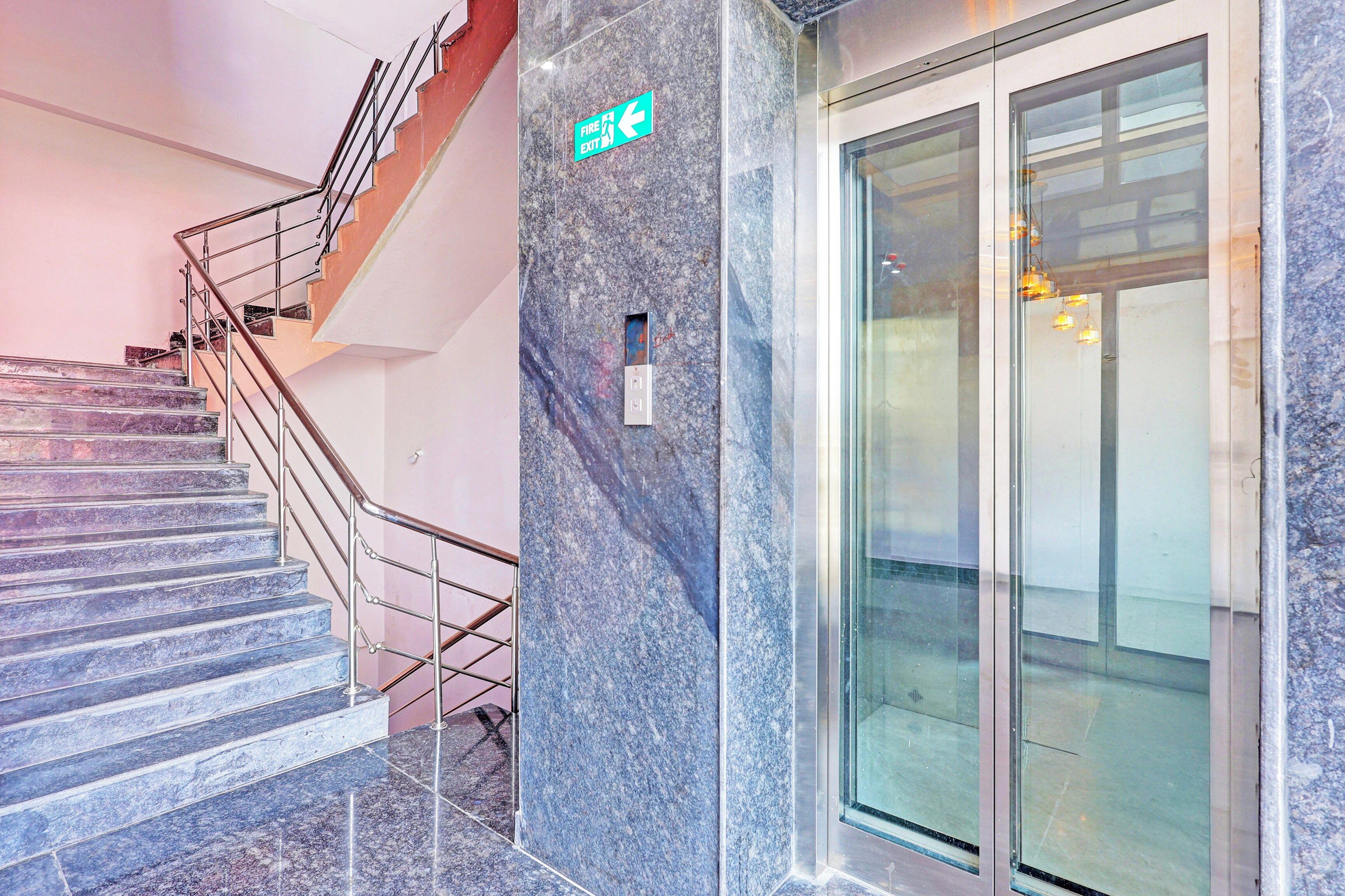 A staircase with metal railings leading to a fire exit sign on a marble wall.