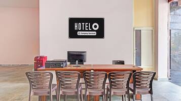 A hotel room with a wooden table, four chairs, a television, and a sign indicating the room is company-serviced.
