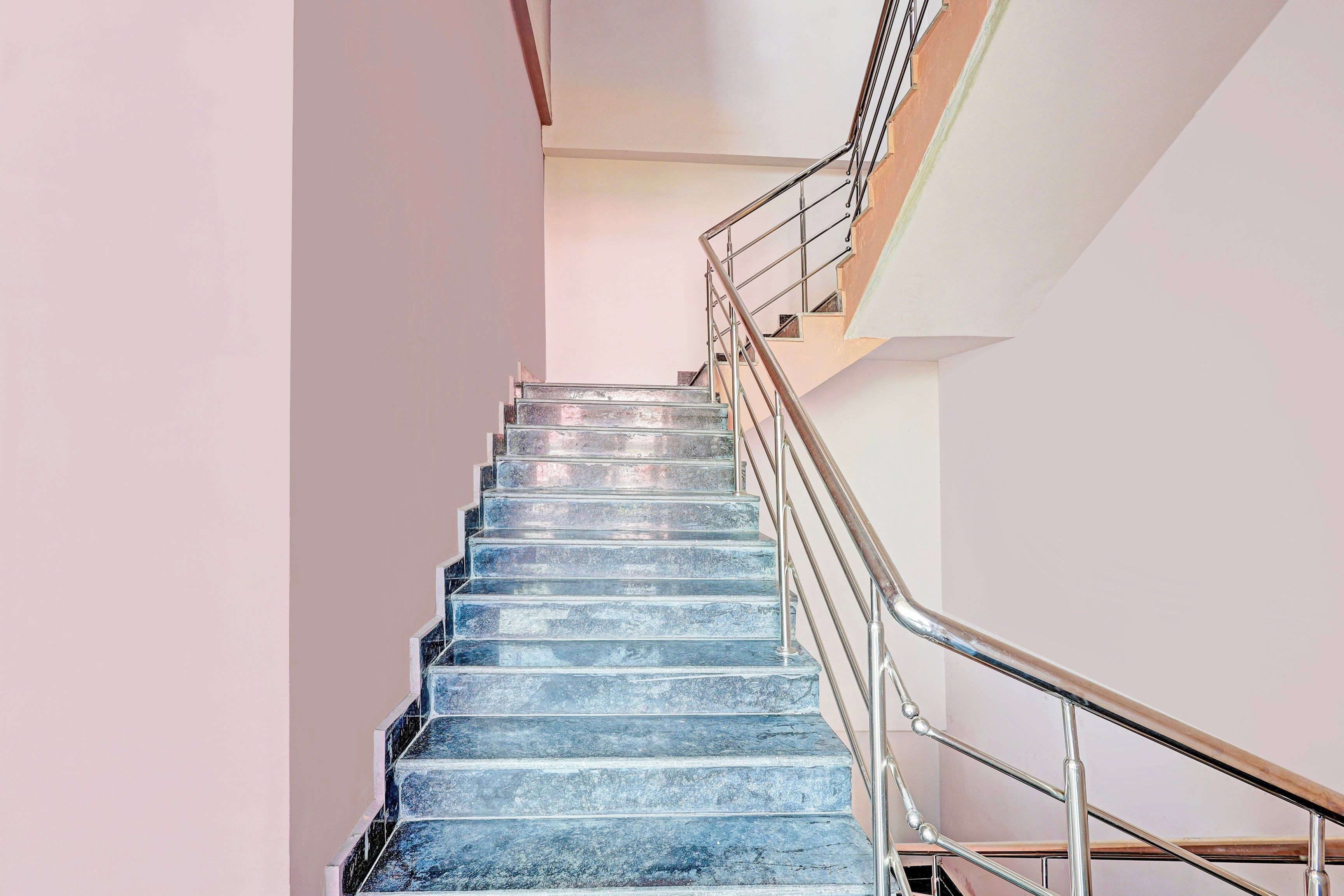 A staircase with metal railings and a handrail, leading to an upper floor.