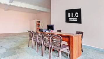 A hotel reception area with a wooden desk, a computer, and a sign indicating the hotel is company-serviced.