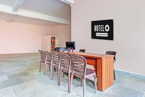 A hotel reception area with a wooden desk, a computer, and a sign indicating the hotel is company-serviced. - OYO Hotel O Ramarvapadu (Vijayawada)