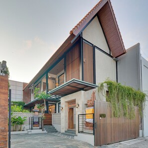 A modern two-story house with a balcony, a staircase leading to the entrance, and a gated area with a wooden fence. - Villa Tajung - Umalas (Badung)