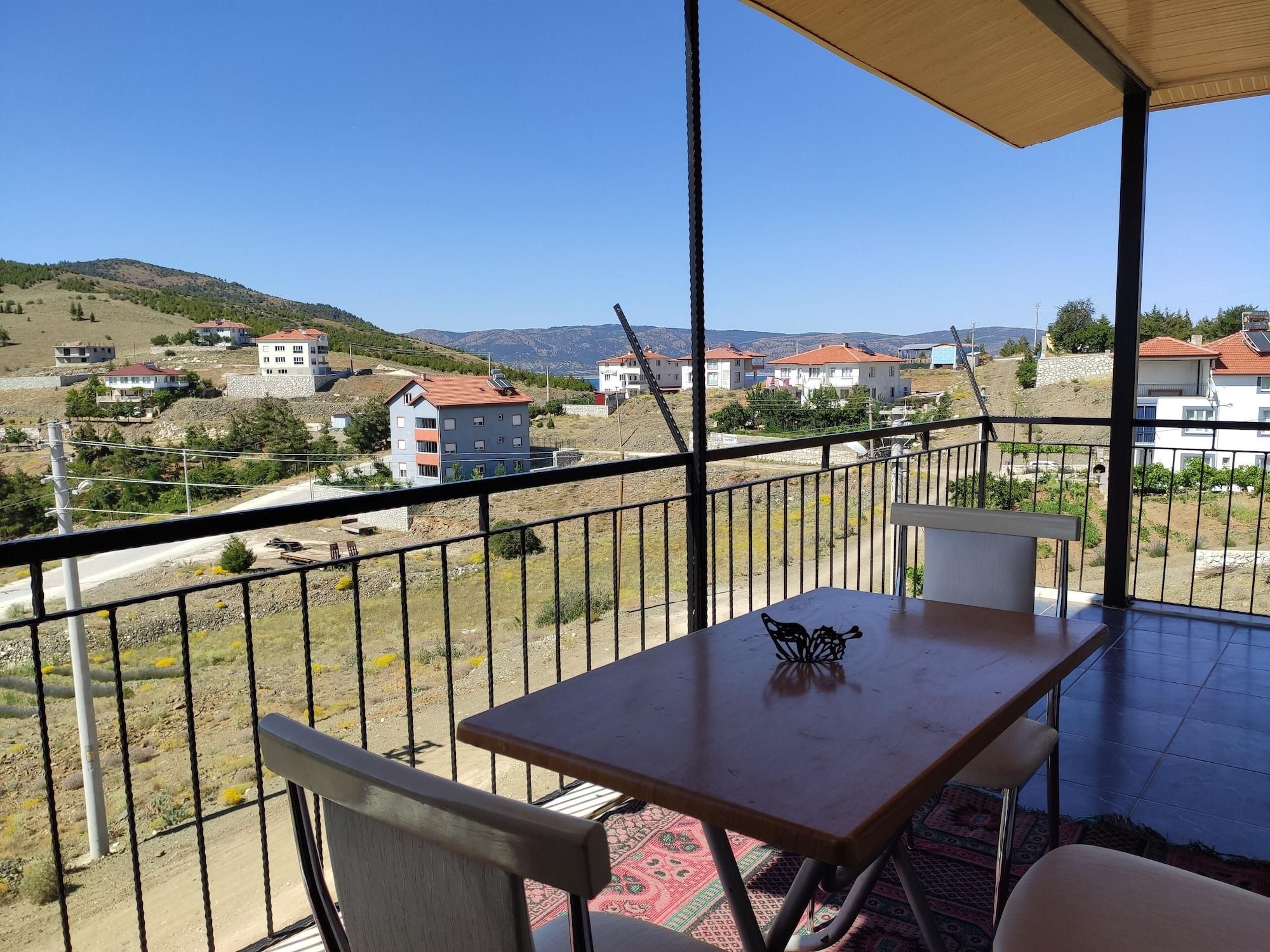 Ein Balkon mit Tisch und Stühlen, der auf einen Wohnbereich mit Häusern und Hügeln blickt.