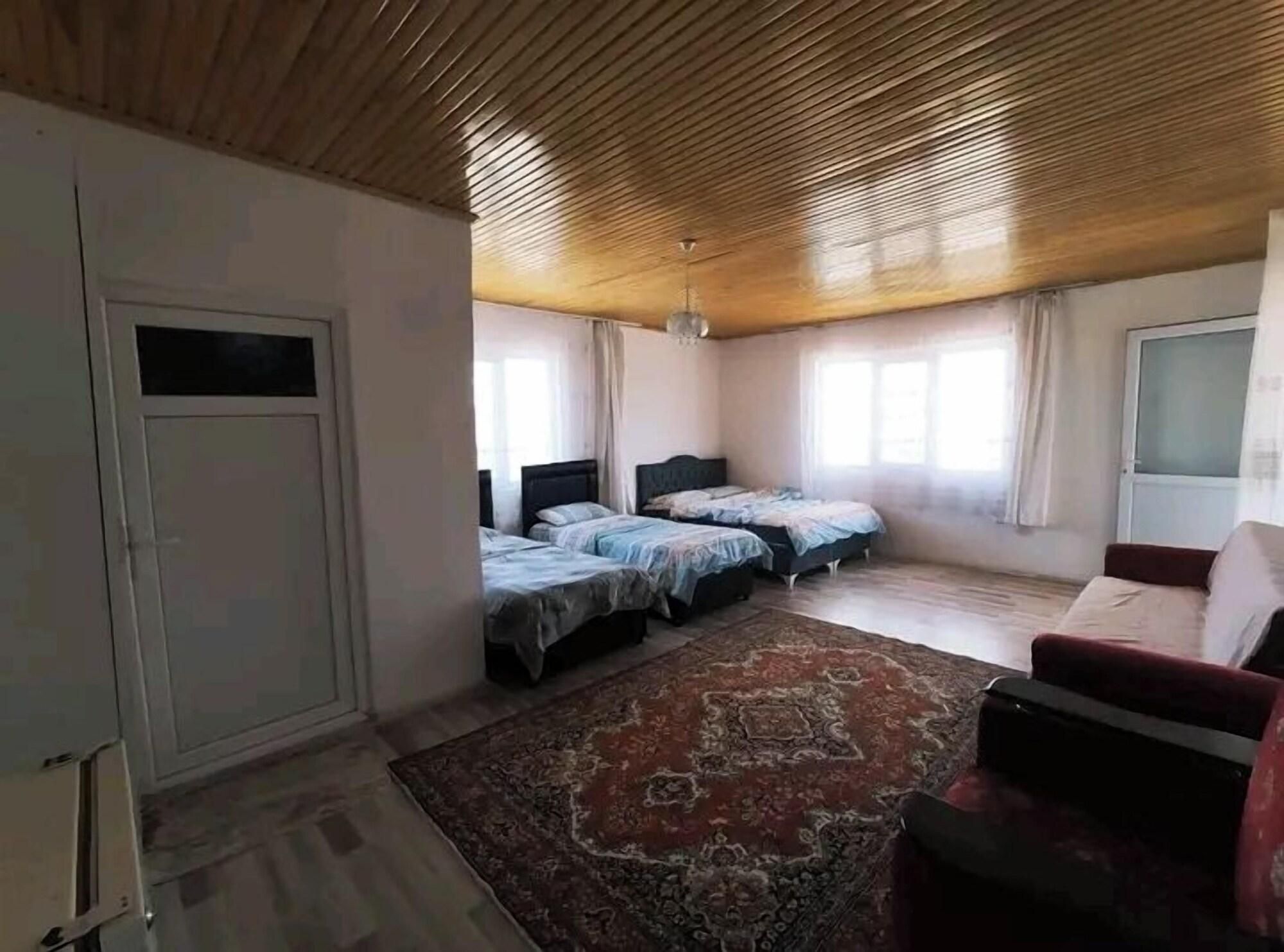 Ein Zimmer mit Holzboden, zwei Betten, einem roten Sofa und einem großen Teppich.