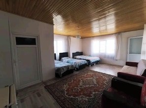Una habitación con techo de madera, dos camas, un sofá rojo y una alfombra grande.