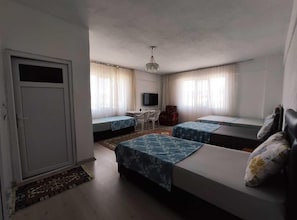 Una habitación con dos camas, un escritorio, una silla, un televisor y un armario.