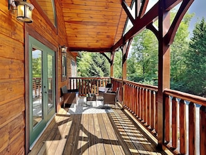 Une terrasse en bois avec une rambarde, un banc et deux chaises.