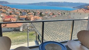 En balkon med udsigt over en kystby, to stole og et lille rundt bord.
