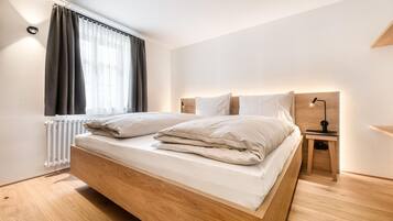 Un dormitorio moderno con una cama de madera, una mesita de noche con una lámpara y una ventana con cortinas.