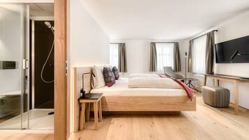 Un dormitorio moderno con una cama grande, un escritorio, un televisor y una zona de ducha.