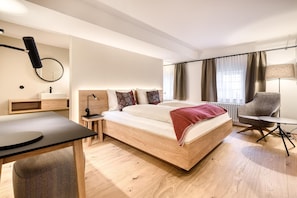 A modern hotel room with a wooden bed, a desk, a chair, and a lamp. - Mã¼nsterhaus (Schruns)