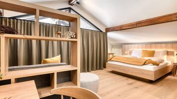 Un dormitorio moderno con cama estilo loft, vigas de madera, escritorio empotrado y un gran ventanal con cortinas.