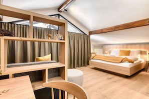 A modern bedroom with a loft-style bed, wooden beams, a built-in desk, and a large window with curtains. - Mã¼nsterhaus (Schruns)