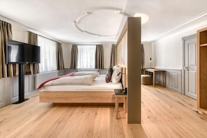 A modern bedroom with a wooden bed, a flat-screen TV, and a bedside table. - Mã¼nsterhaus (Schruns)