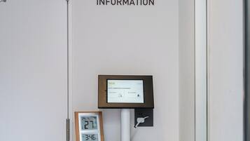 Un quiosco digital informativo con una pantalla que muestra detalles del hotel, un reloj y un letrero superior que dice 'INFORMATION'.