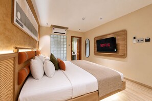 Une chambre d’hôtel moderne avec un grand lit, un téléviseur fixé au mur et un appareil de climatisation visible.