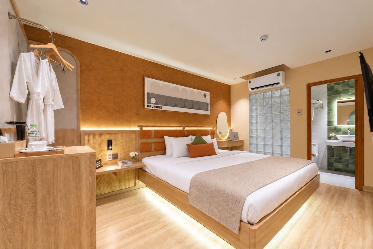 Une chambre d’hôtel moderne avec un grand lit, une table de chevet et un bureau avec une chaise.