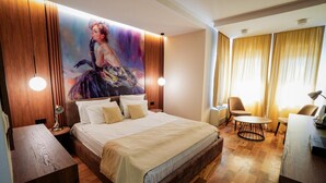 A hotel room with a large bed, a desk, a chair, and a painting on the wall. - Hotel City In (Kocani)