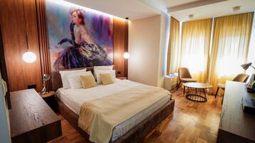 Ein Hotelzimmer mit einem großen Bett, einem Schreibtisch, einem Stuhl und einem Gemälde an der Wand.