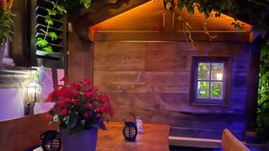 An indoor seating area with wooden benches and a table, surrounded by greenery and a small window. - Hotel Sternen Worb (Worb)