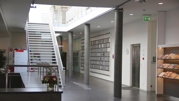 Een modern interieur met een trap, boekenkasten en een lift.