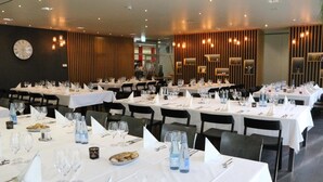 Een restaurant met meerdere tafels voor diners, voorzien van witte tafelkleden, glazen en bestek.