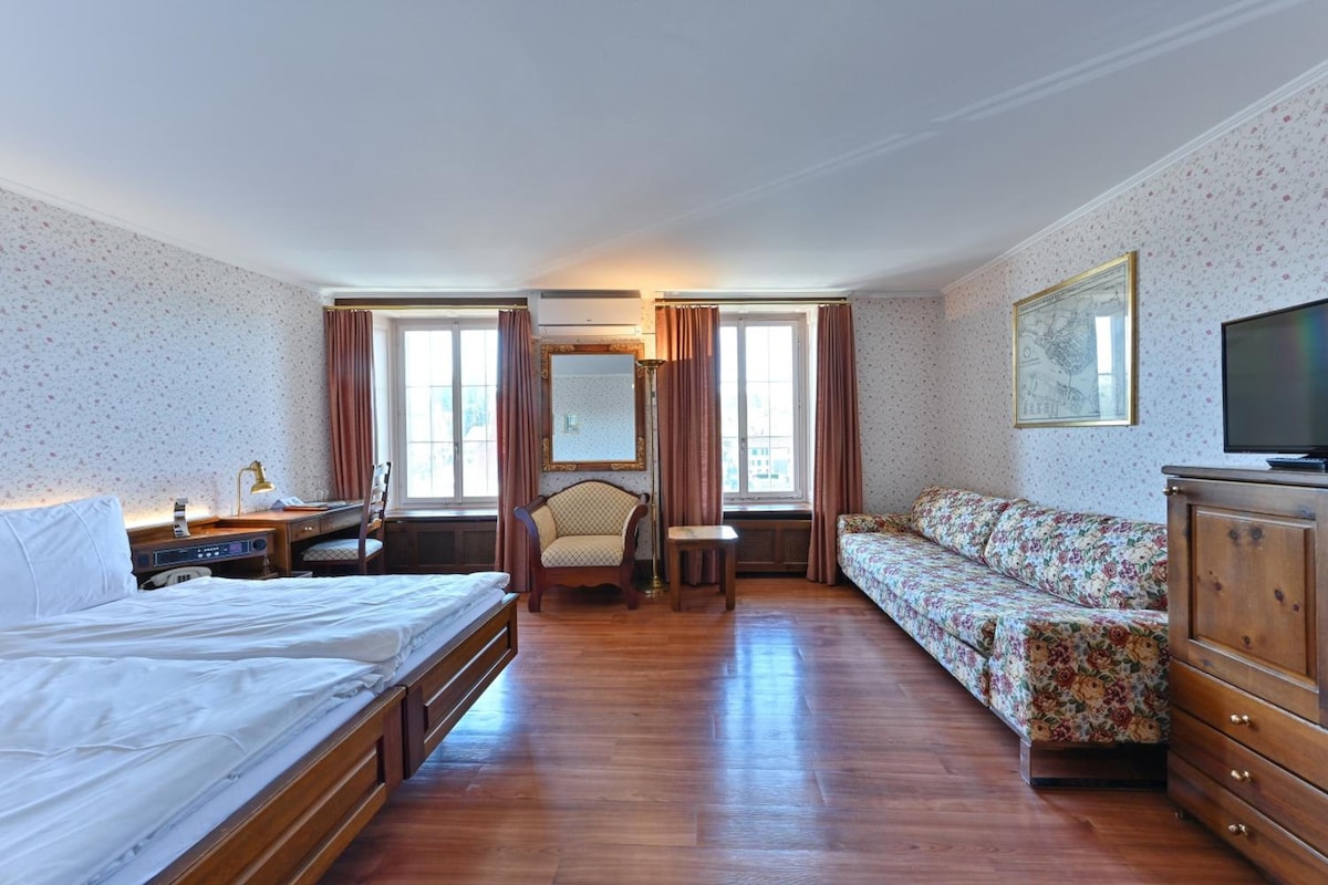Una habitación de hotel con cama, escritorio, silla, sofá, televisor y cómoda.