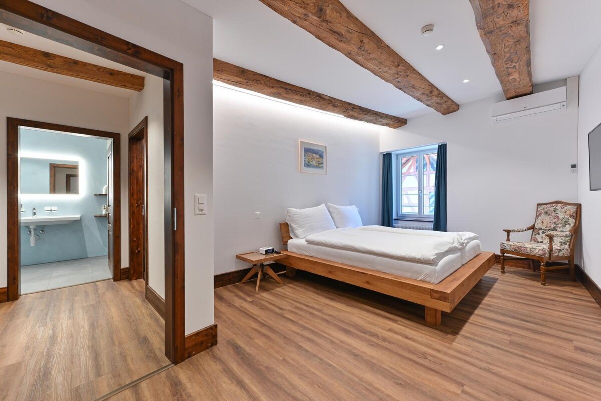 Un dormitorio con cama de madera, una silla y vistas al exterior.