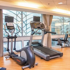 Une salle de sport équipée de tapis de course, d’appareils elliptiques et de vélos d’appartement.