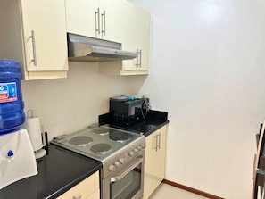 A kitchen with a stove, oven, and cabinets. - Grand Cenia Residence with 2 Bedrooms Condo Unit (Cebu City)
