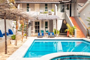 A swimming pool with lounge chairs and a covered seating area. - B4 Boutique (Paje)