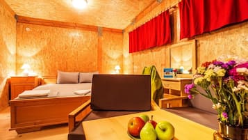 A wooden room with a bed, a desk, and a table with fruit.