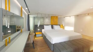 Una habitación de hotel moderna con una cama grande, mesitas de noche, un área de descanso y un espejo amplio.