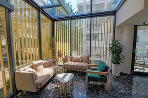 A modern interior with a glass ceiling, a beige sofa, a green armchair, and a small table. - Dorchester Hotel (Ksamil)