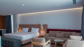 Una habitación de hotel moderna con una cama, un sofá, una mesita y una silla.