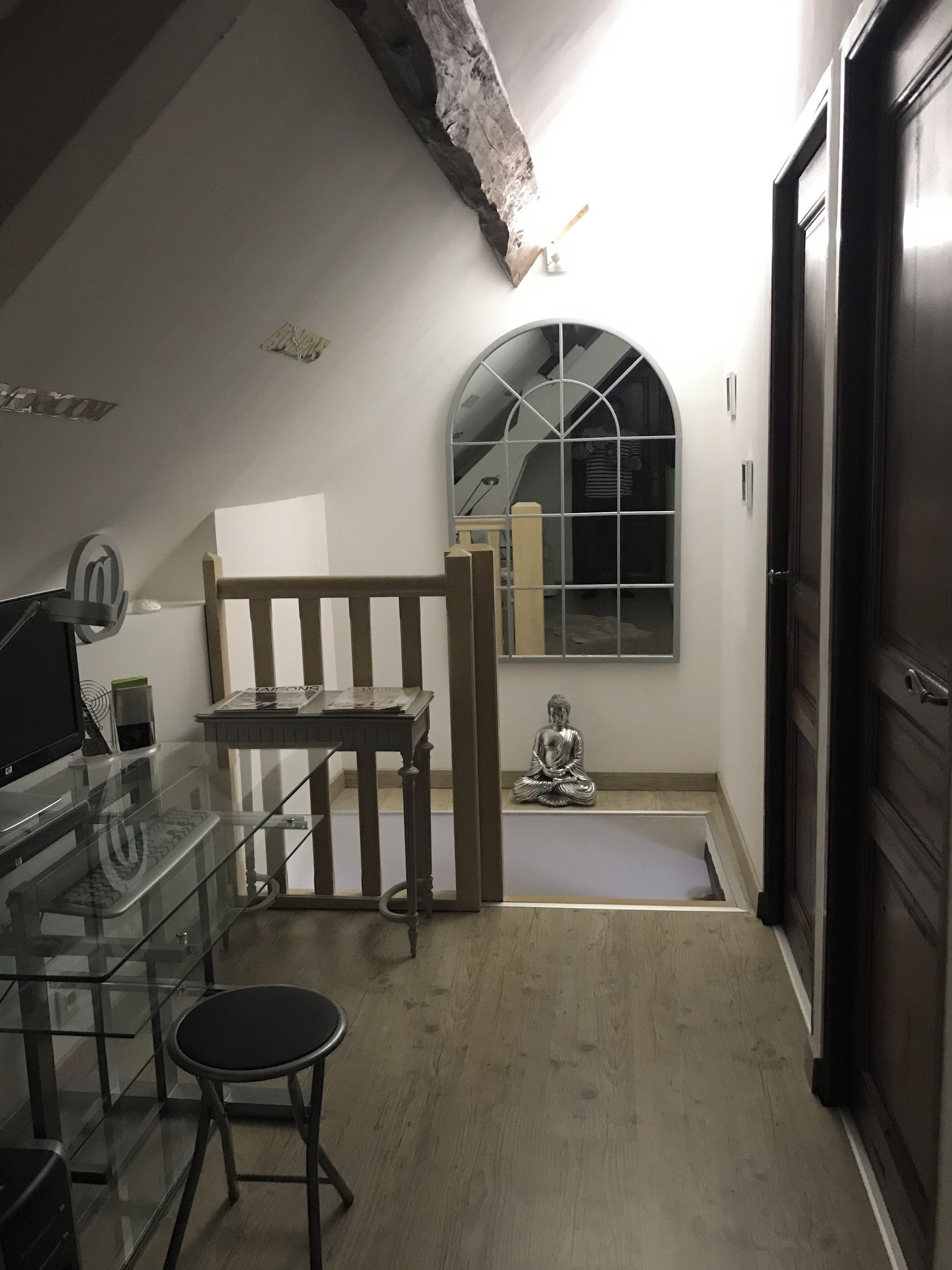 A room with a glass table, a wooden bench, a Buddha statue, and a door.
