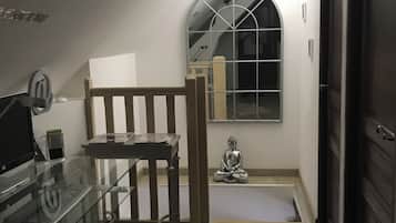 A room with a glass table, a wooden bench, a Buddha statue, and a door.