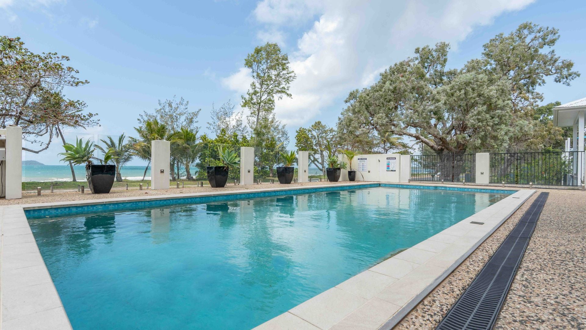 A rectangular swimming pool with a clear blue water surface, surrounded by a pebble-lined deck.