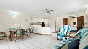 A modern living room with a dining area, kitchen, and a bedroom with a view. - Sea Views on Kennedy (South Mission Beach)